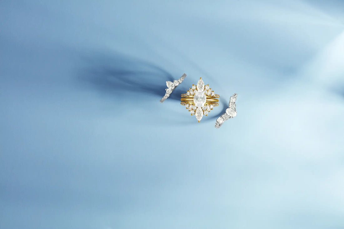 a yellow gold wedding set against a light blue background