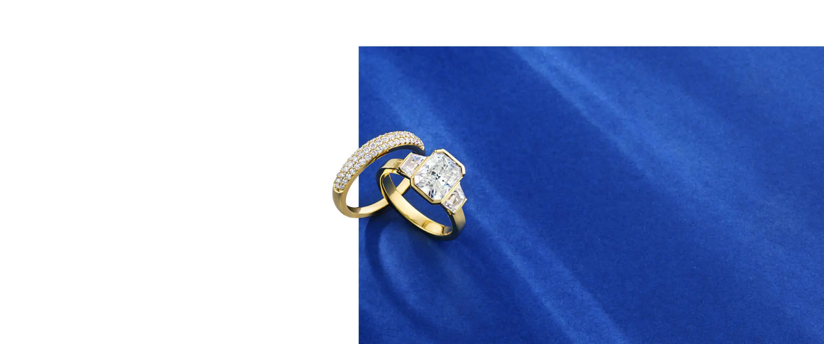Yellow gold engagement and wedding rings against a white and blue background 