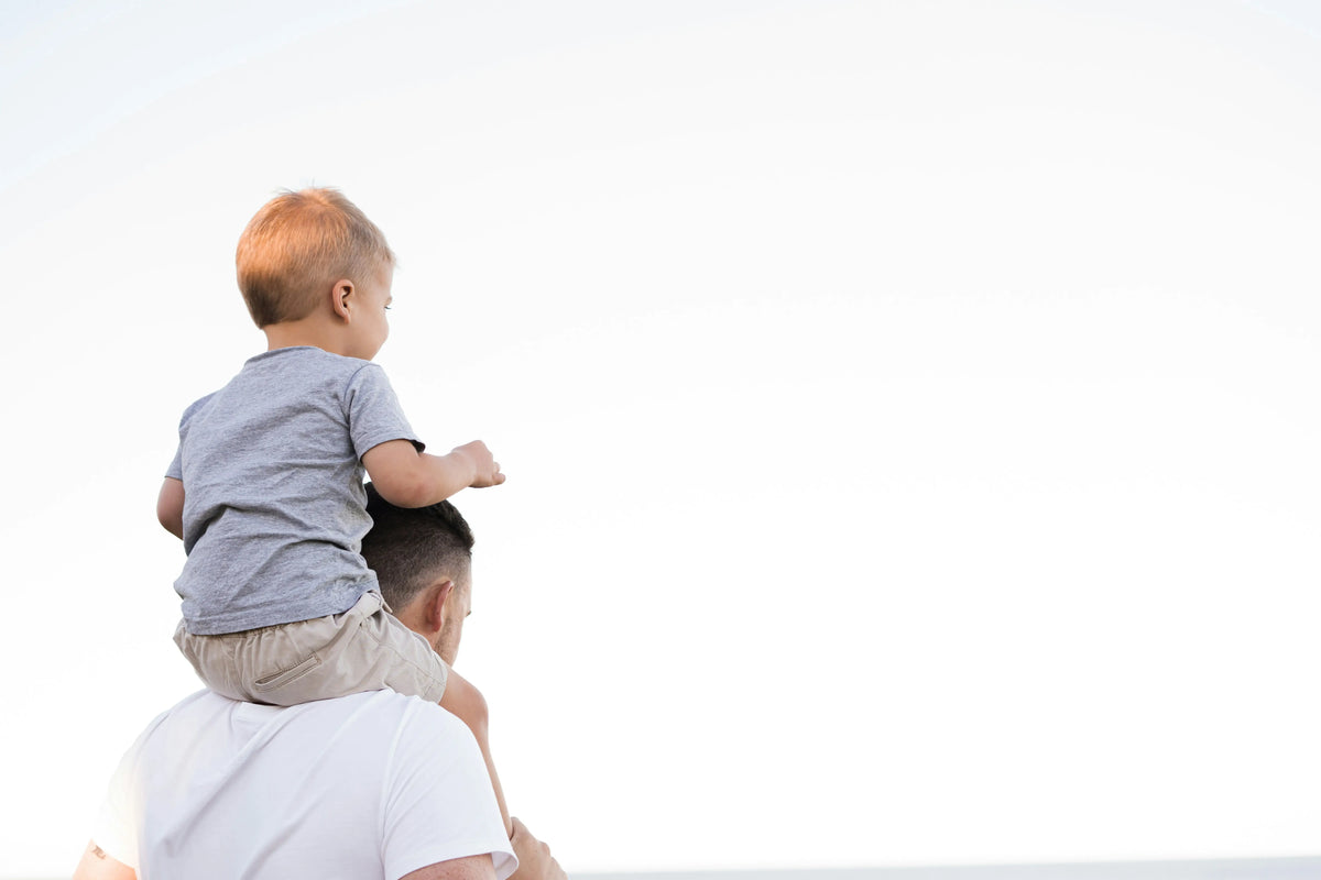 A little boy sitting on his father's shoulders