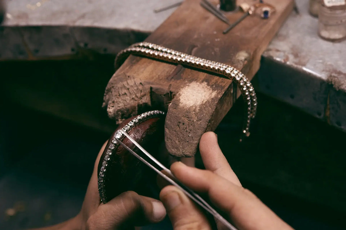 Man repairing diamond tennis bracelets at jeweler's bench