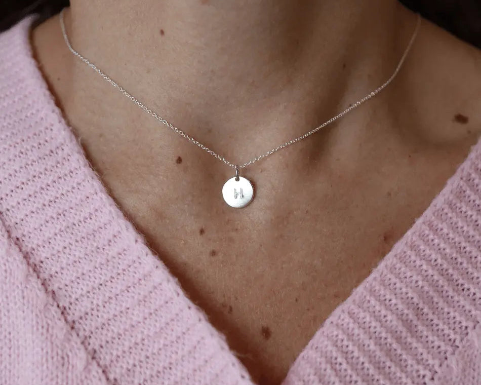 Sterling silver initial pendant necklace on woman's neck