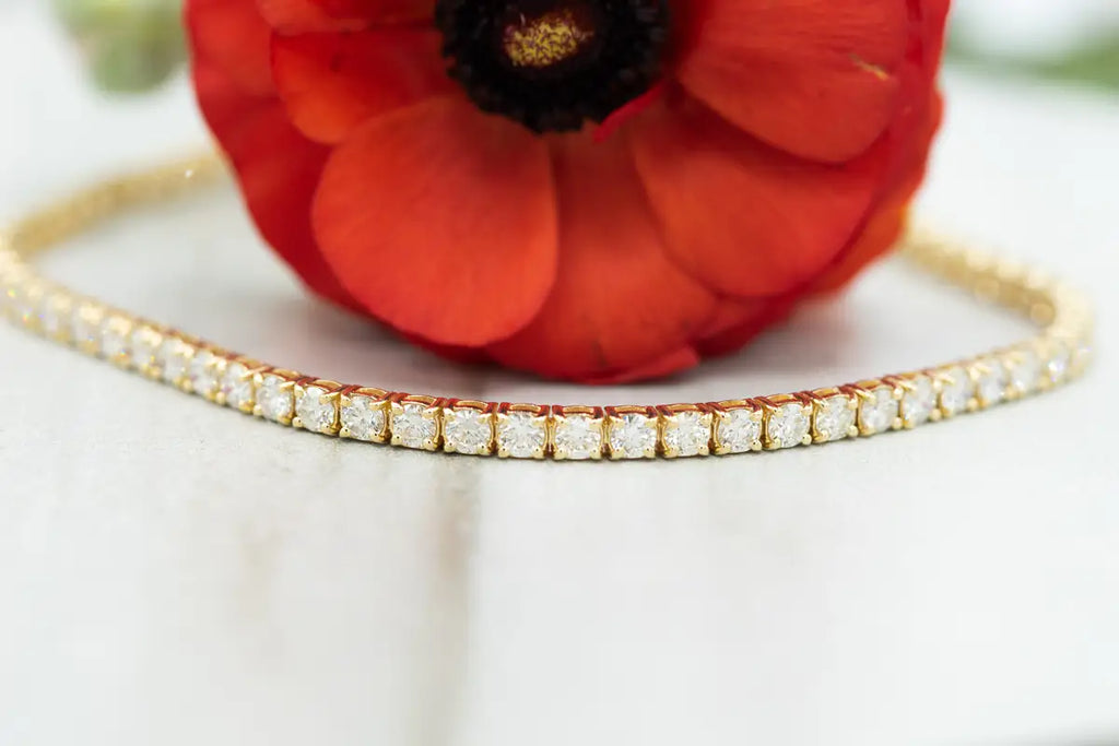 Diamond tennis bracelet in front of red flower