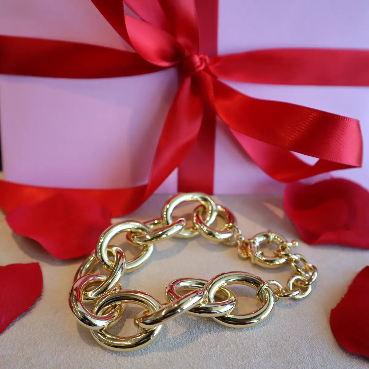 Gorjana gold chunky link bracelet with present behind it