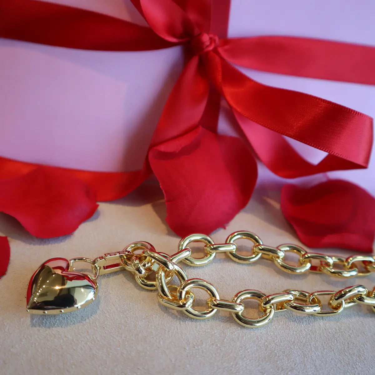 Gorjana gold heart link bracelet with present behind it