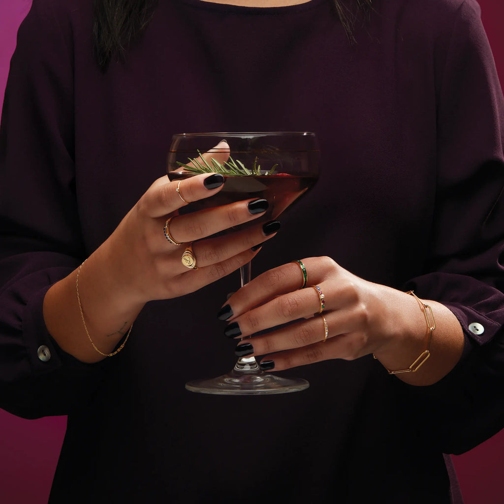 Women hand holding drink and wearing bracelets & rings