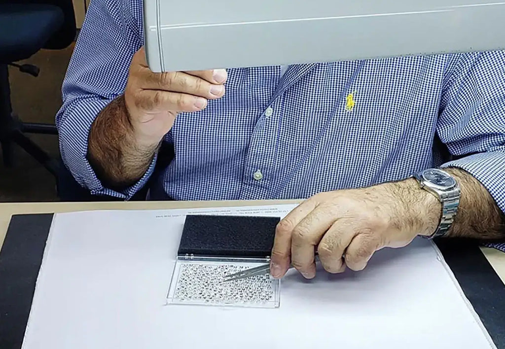 man picking loose diamonds with tweezers